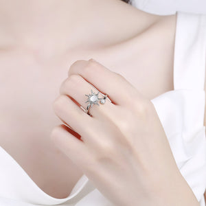 Woman's hand wearing a sun fidget ring for anxiety against a white blouse